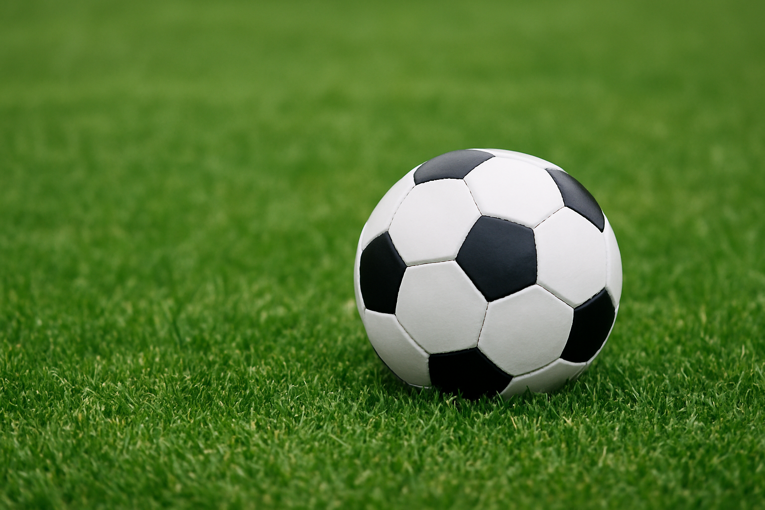 Black and white soccer ball resting on a bright green grass field in Frisco.